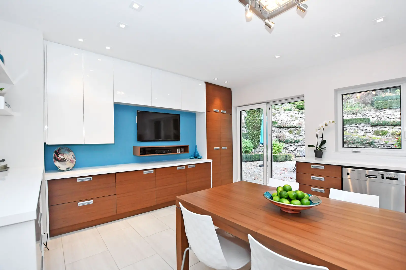 Interior of a house on Plymbridge Road in North York, with wood floors, a white kitchen, and windows onto the trees.