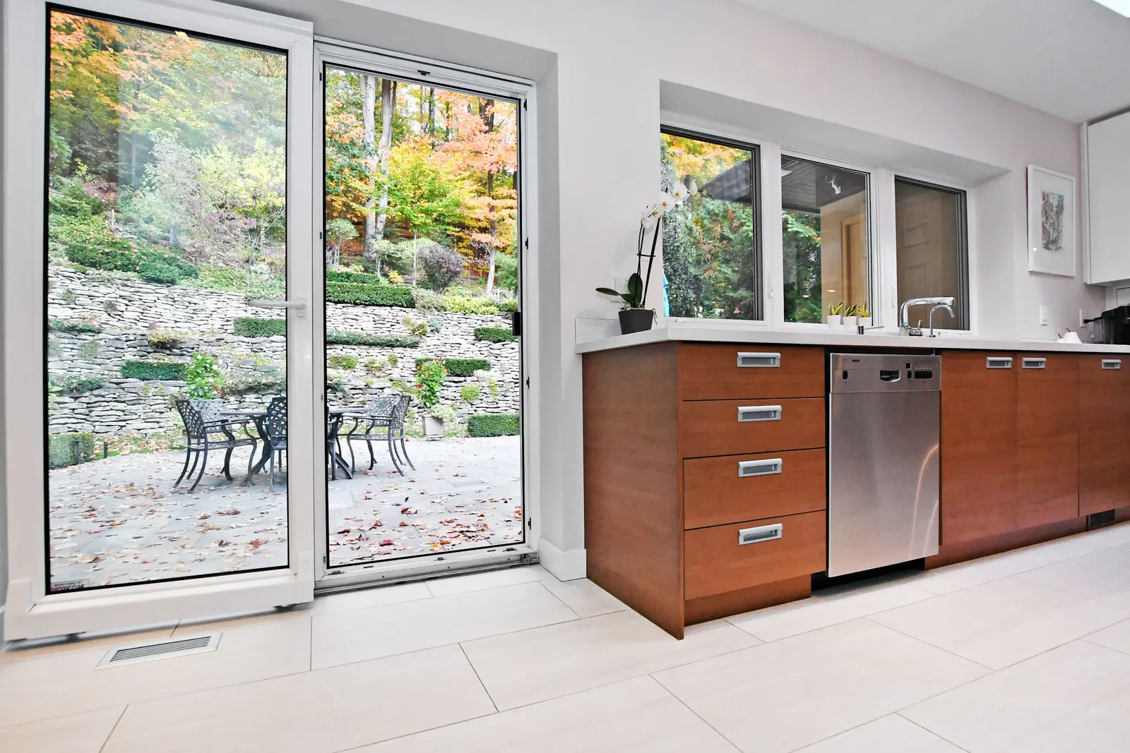 Interior of a house on Plymbridge Road in North York, with wood floors, a white kitchen, and windows onto the trees.