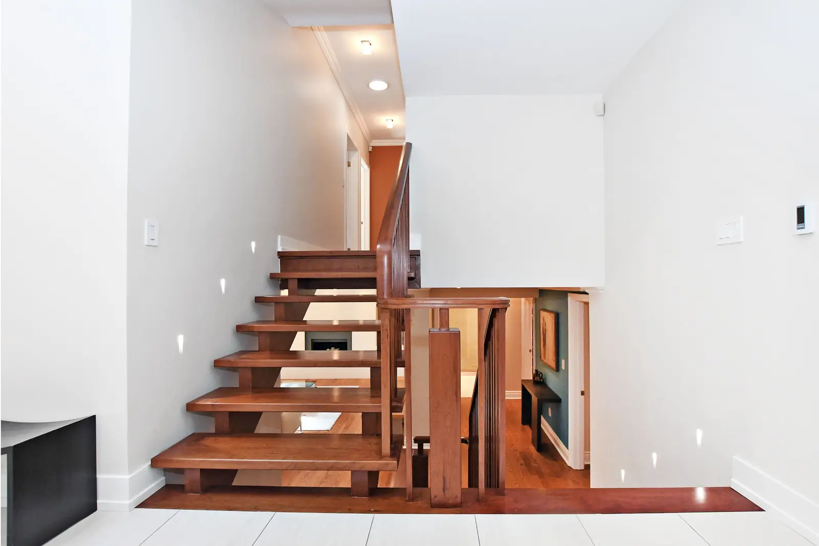Interior of a house on Plymbridge Road in North York, with wood floors, a white kitchen, and windows onto the trees.