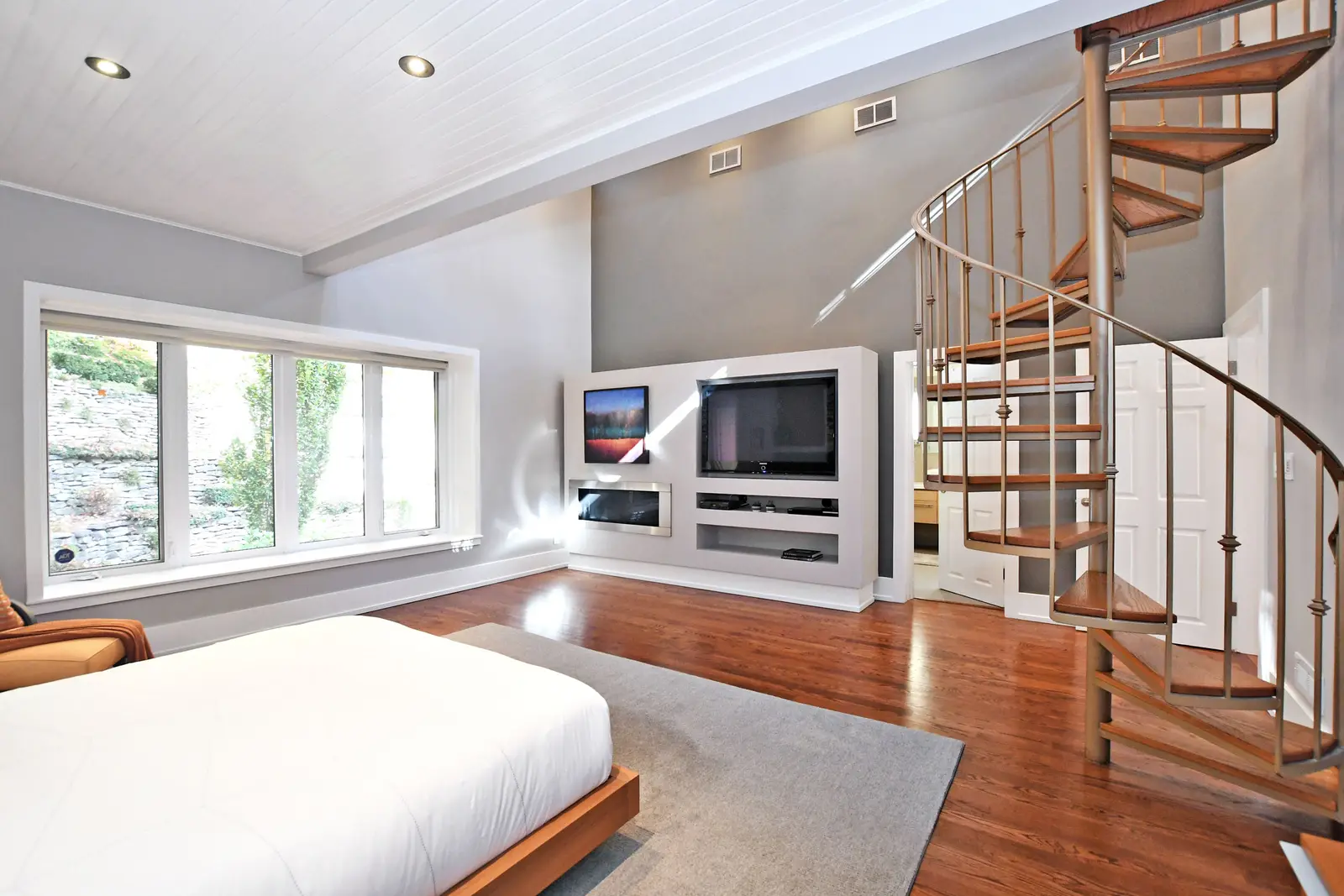 Interior of a house on Plymbridge Road in North York, with wood floors, a white kitchen, and windows onto the trees.