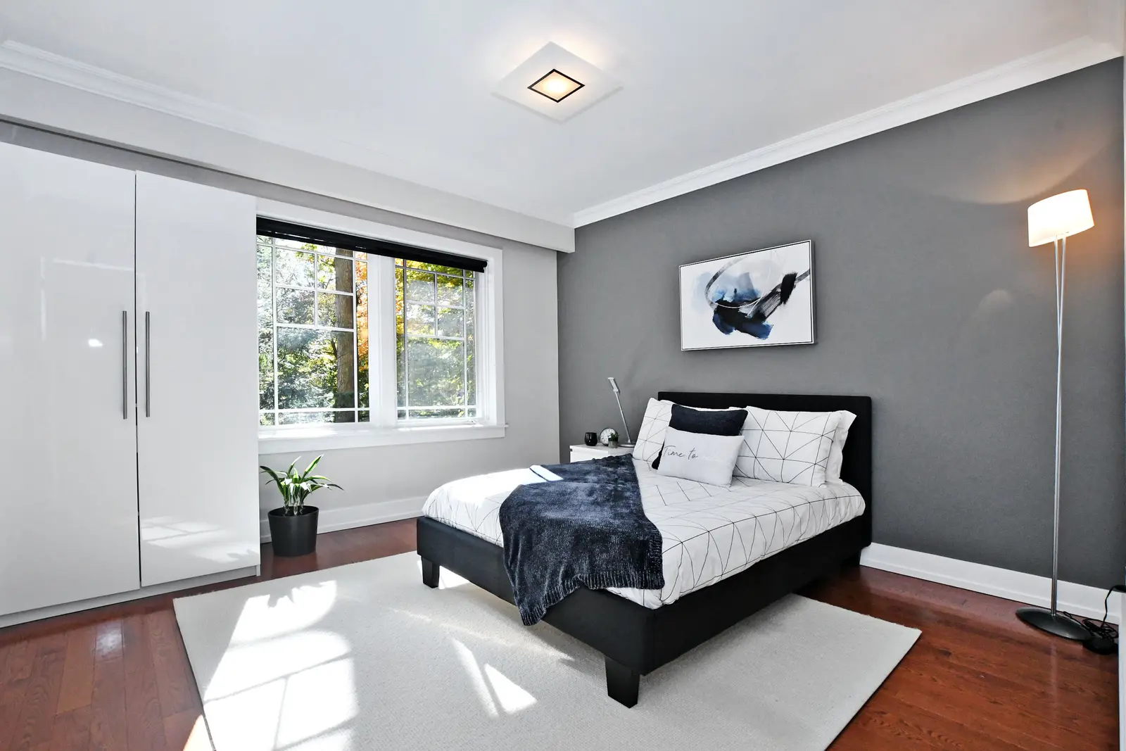 Interior of a house on Plymbridge Road in North York, with wood floors, a white kitchen, and windows onto the trees.