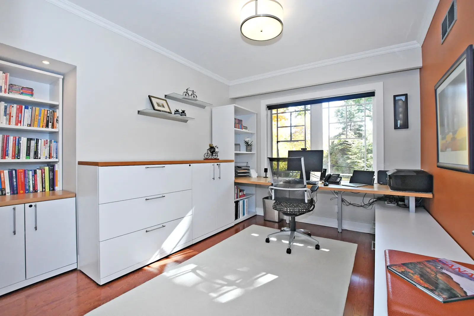 Interior of a house on Plymbridge Road in North York, with wood floors, a white kitchen, and windows onto the trees.