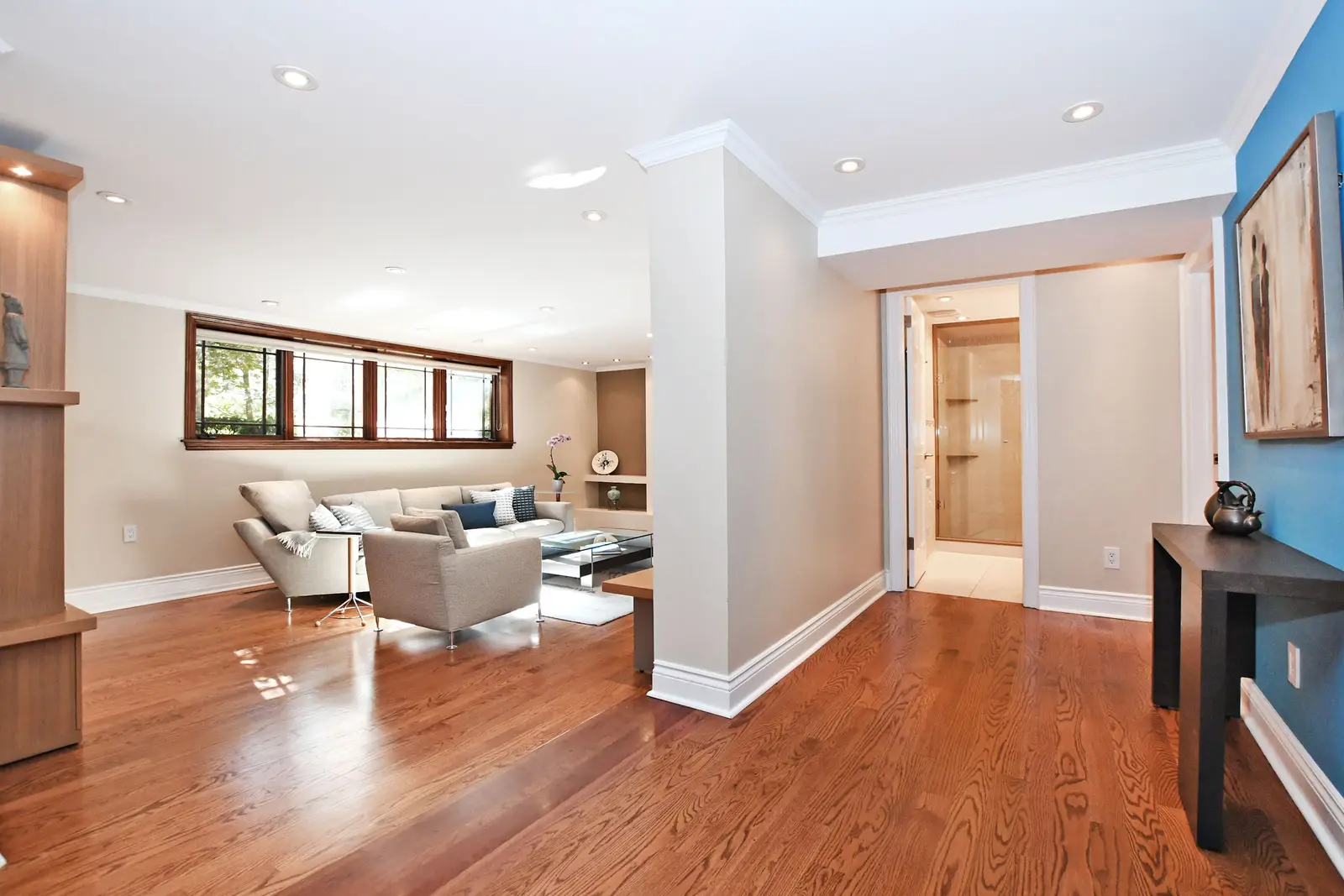 Interior of a house on Plymbridge Road in North York, with wood floors, a white kitchen, and windows onto the trees.
