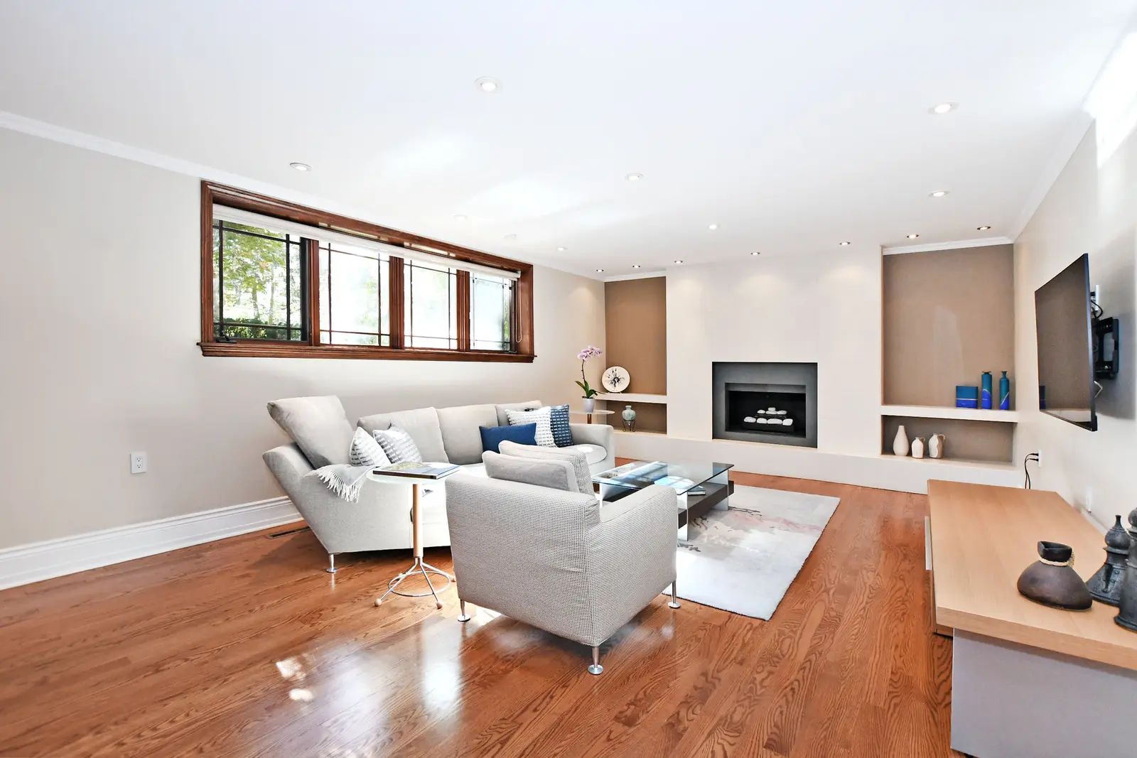 Interior of a house on Plymbridge Road in North York, with wood floors, a white kitchen, and windows onto the trees.