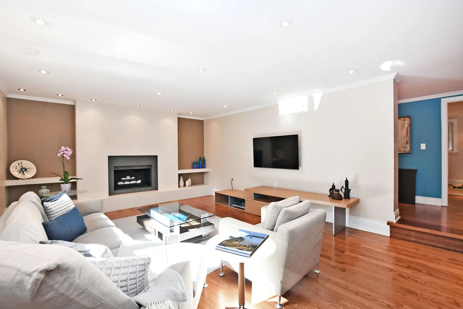 Interior of a house on Plymbridge Road in North York, with wood floors, a white kitchen, and windows onto the trees.