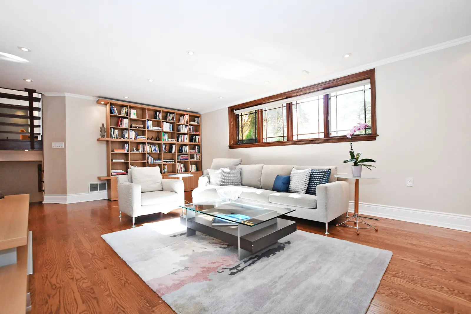 Interior of a house on Plymbridge Road in North York, with wood floors, a white kitchen, and windows onto the trees.