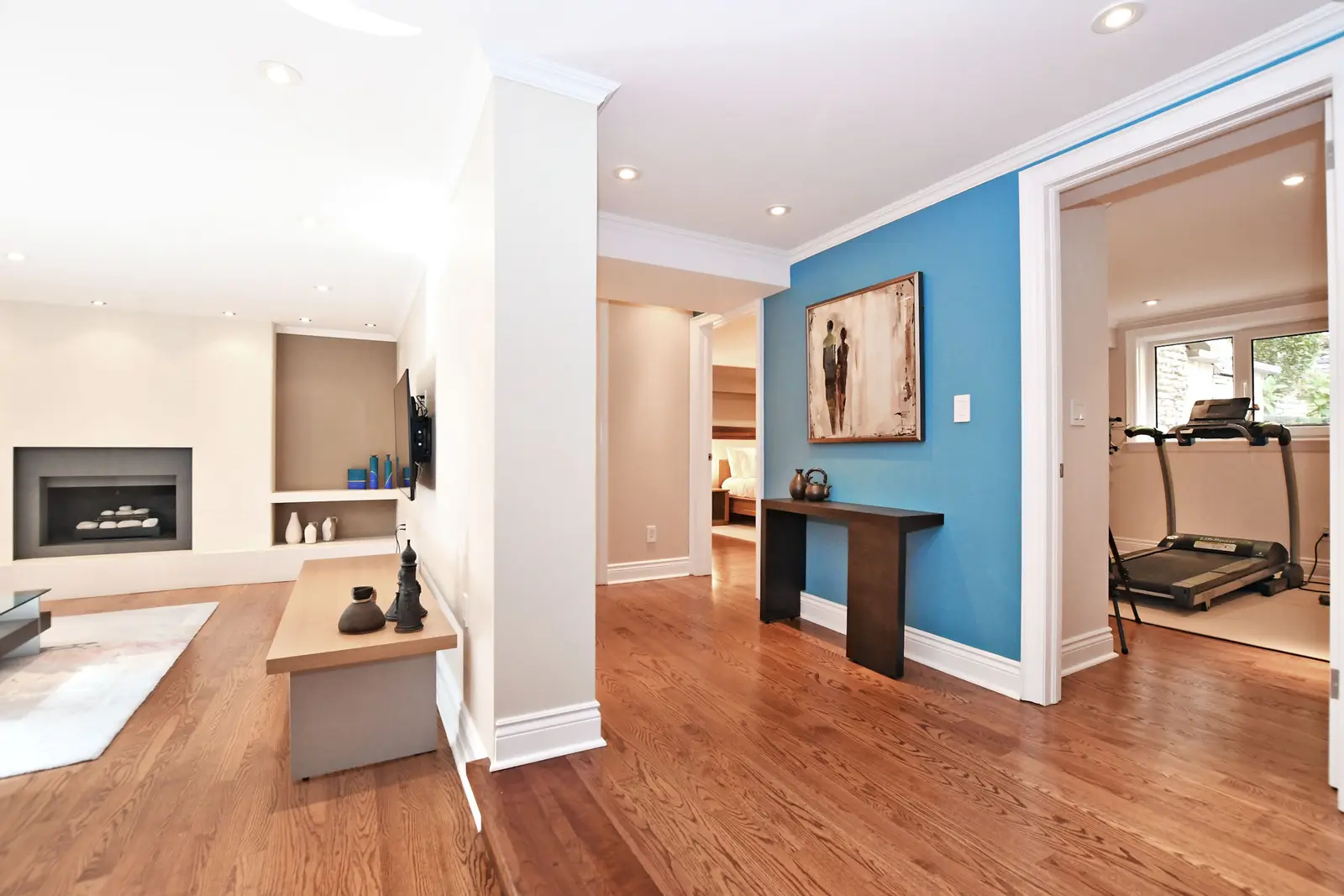 Interior of a house on Plymbridge Road in North York, with wood floors, a white kitchen, and windows onto the trees.